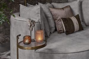Loungebank met organische vormen en bijpassende rugkussens in een grijze velvet stof, en gouden en bronzen accessoires.