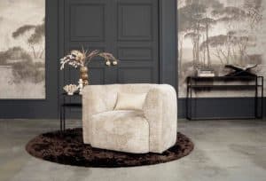 beige fauteuil met ronde en organische vormen in de armleuning, rugleuning en zitting. Gestyled met natuurlijke materialen en beige en zwarte woonaccessoires.