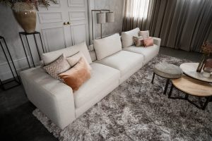 Beige bank met verschillende elementen en een sfeervolle rood / roze interieurstyling.
